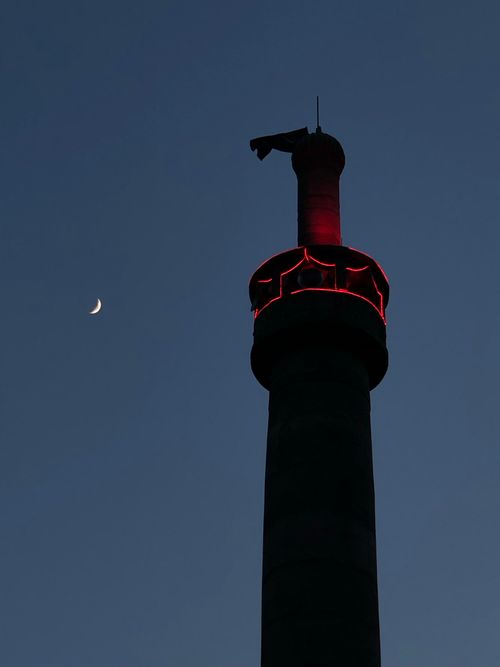 Free Silhouetted minaret with red lighting and crescent moon in twilight sky, serene and sacred. Stock Photo