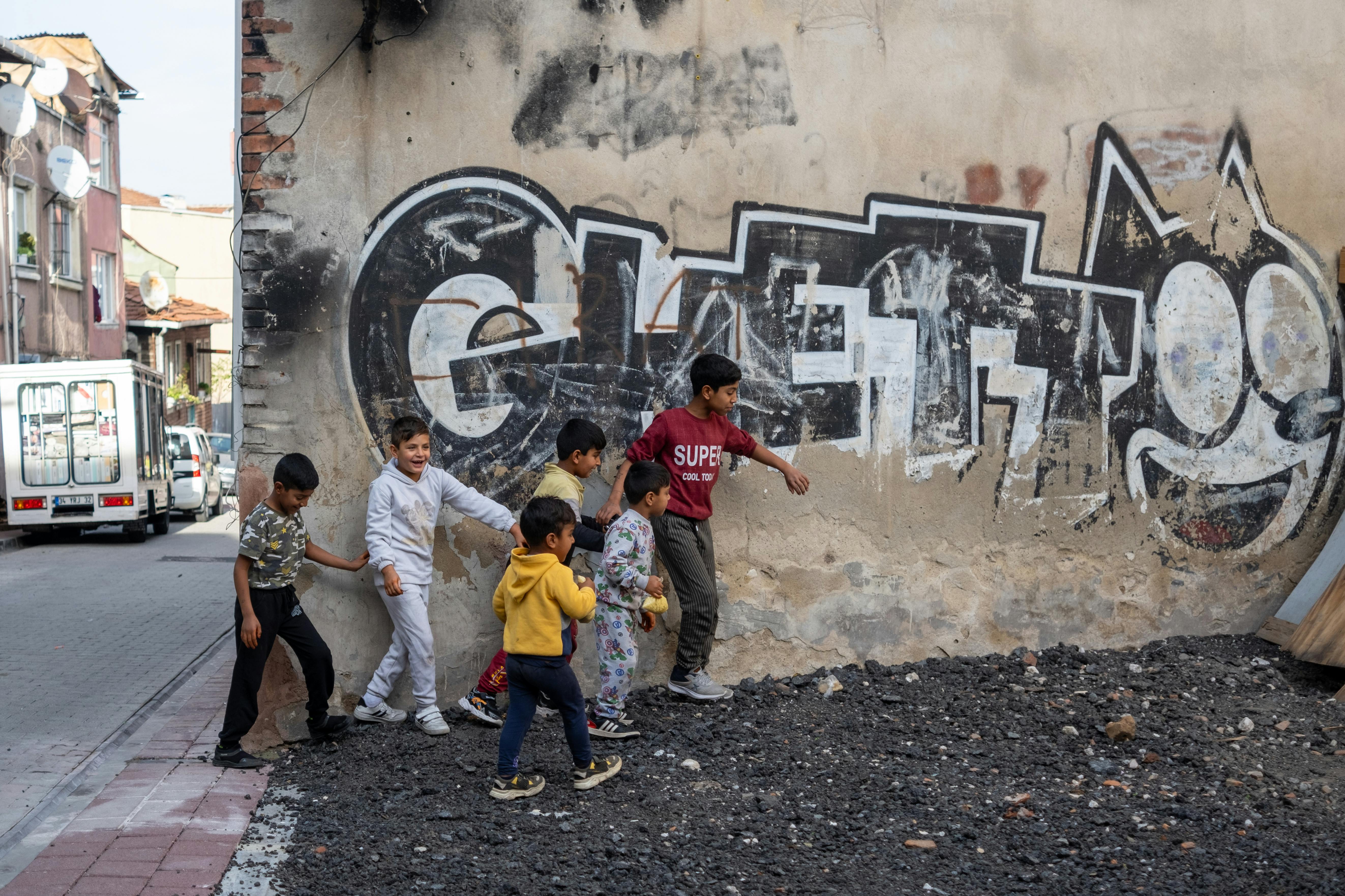 a group of children playing in front of a wall with graffiti