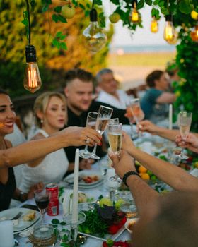 A cheerful group of adults enjoying an outdoor dining celebration with champagne toasts.