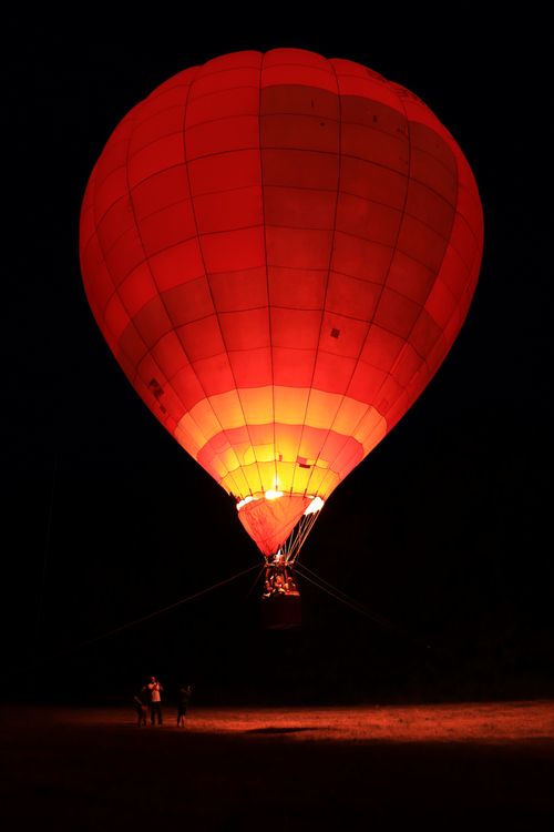 Free A glowing hot air balloon illuminates the night sky, offering an adventurous ride. Stock Photo