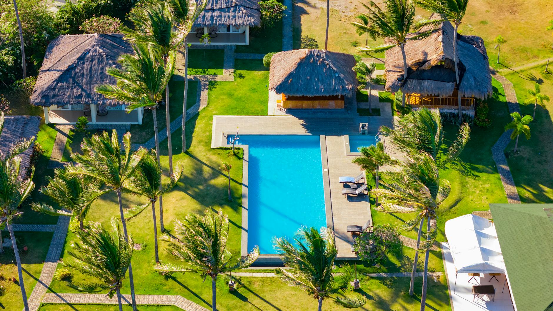 Stunning aerial view of a tropical resort with a pool, lush greenery, and palm trees in Bacong, Philippines.