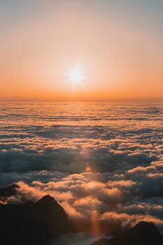 Vibrant sunrise above the clouds in Madeira, Portugal showcasing dramatic mountain silhouettes.