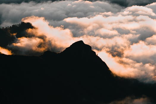 Breathtaking sunrise over Madeira's mountain peaks with clouds ablaze in warm hues.