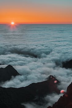 A stunning sunset view over clouds and mountains in Madeira, Portugal, "captured in vivid colors.