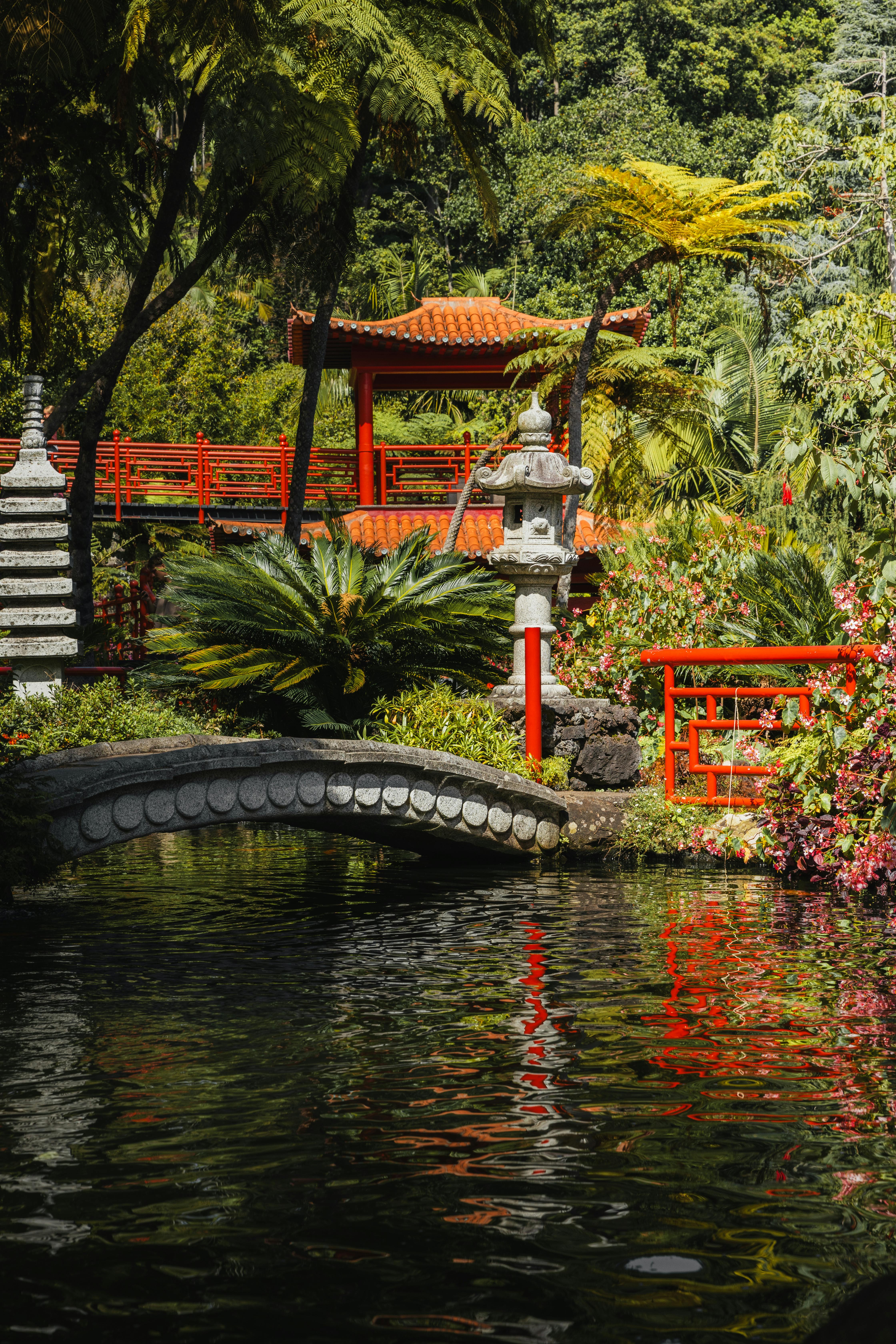 a red bridge over a pond with a garden