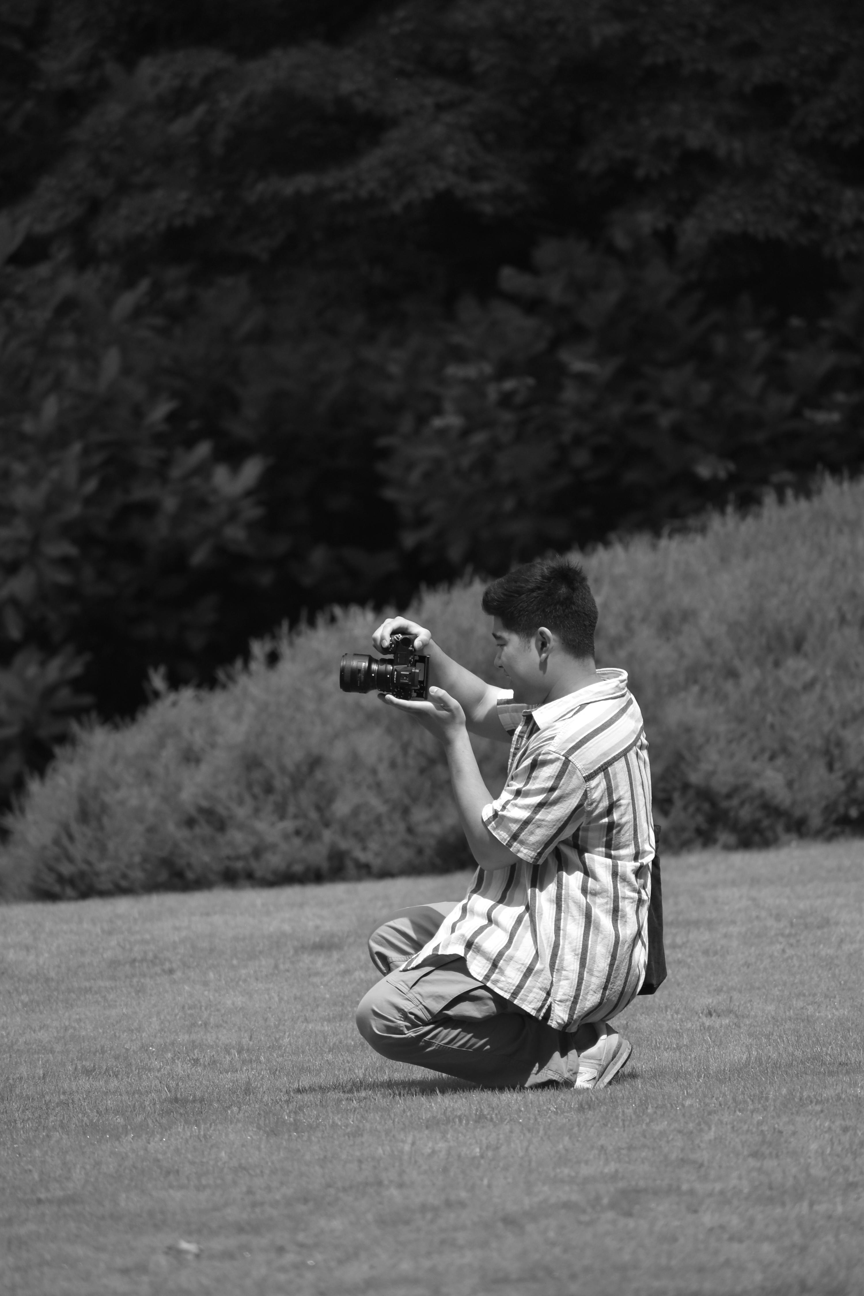 a man crouching down in the grass with a camera