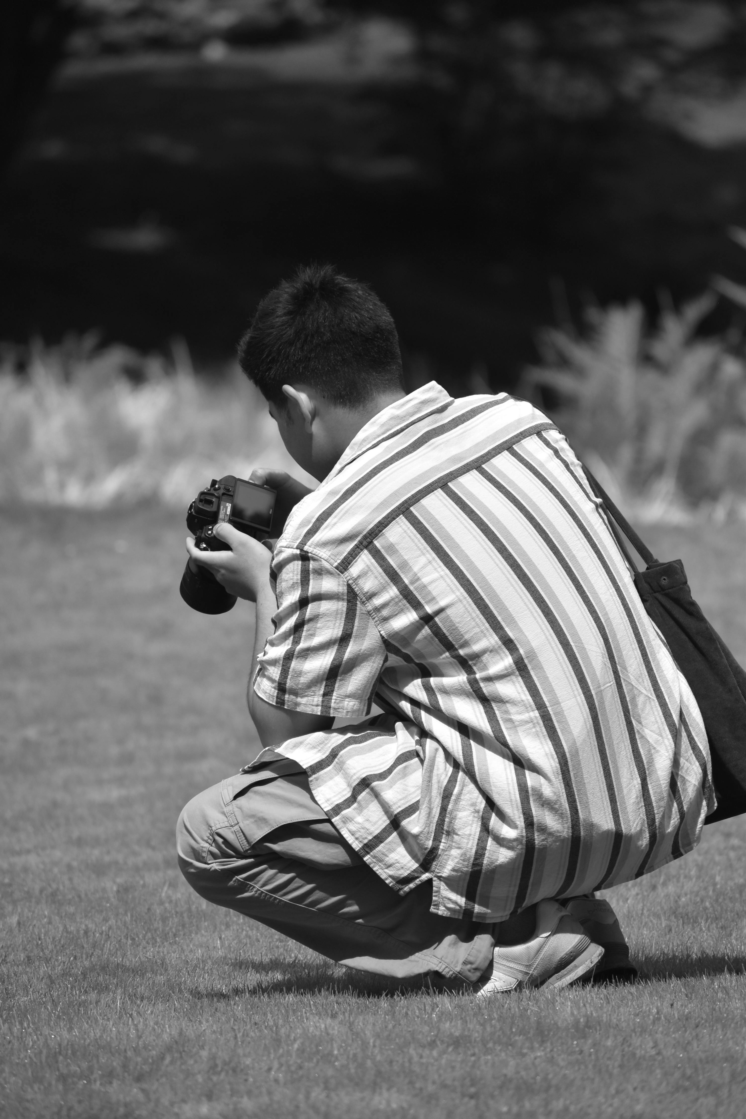 a man crouching down in the grass with his camera