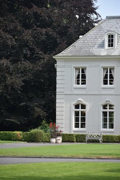 Stunning white house with a lush garden and hedge, ideal for elegant living.