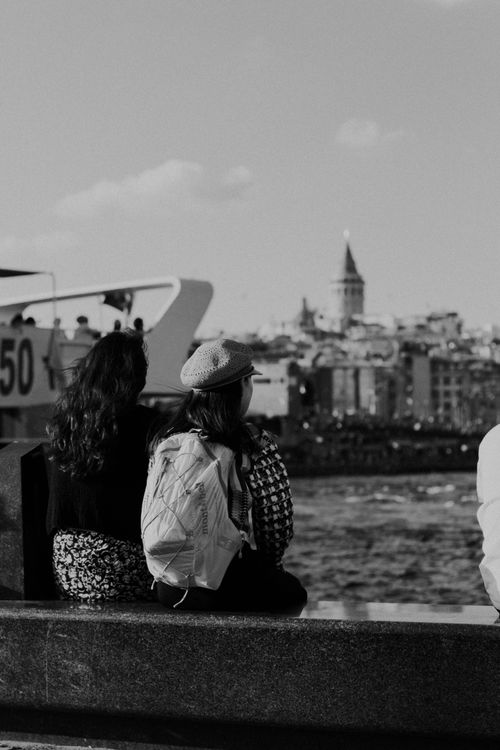 Free Candid street photograph of two women by the Bosphorus with Galata Tower in Istanbul. Stock Photo