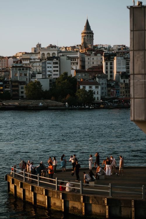 Free A beautiful view of Istanbul's Galata Tower overlooking the bustling waterfront at sunset. Stock Photo