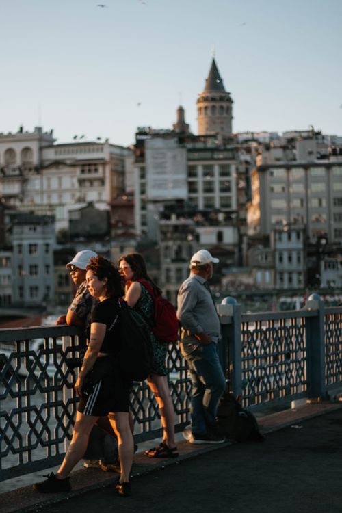 Free Tourists explore Galata Bridge with a view of Istanbul's historic skyline during a sunny day. Stock Photo