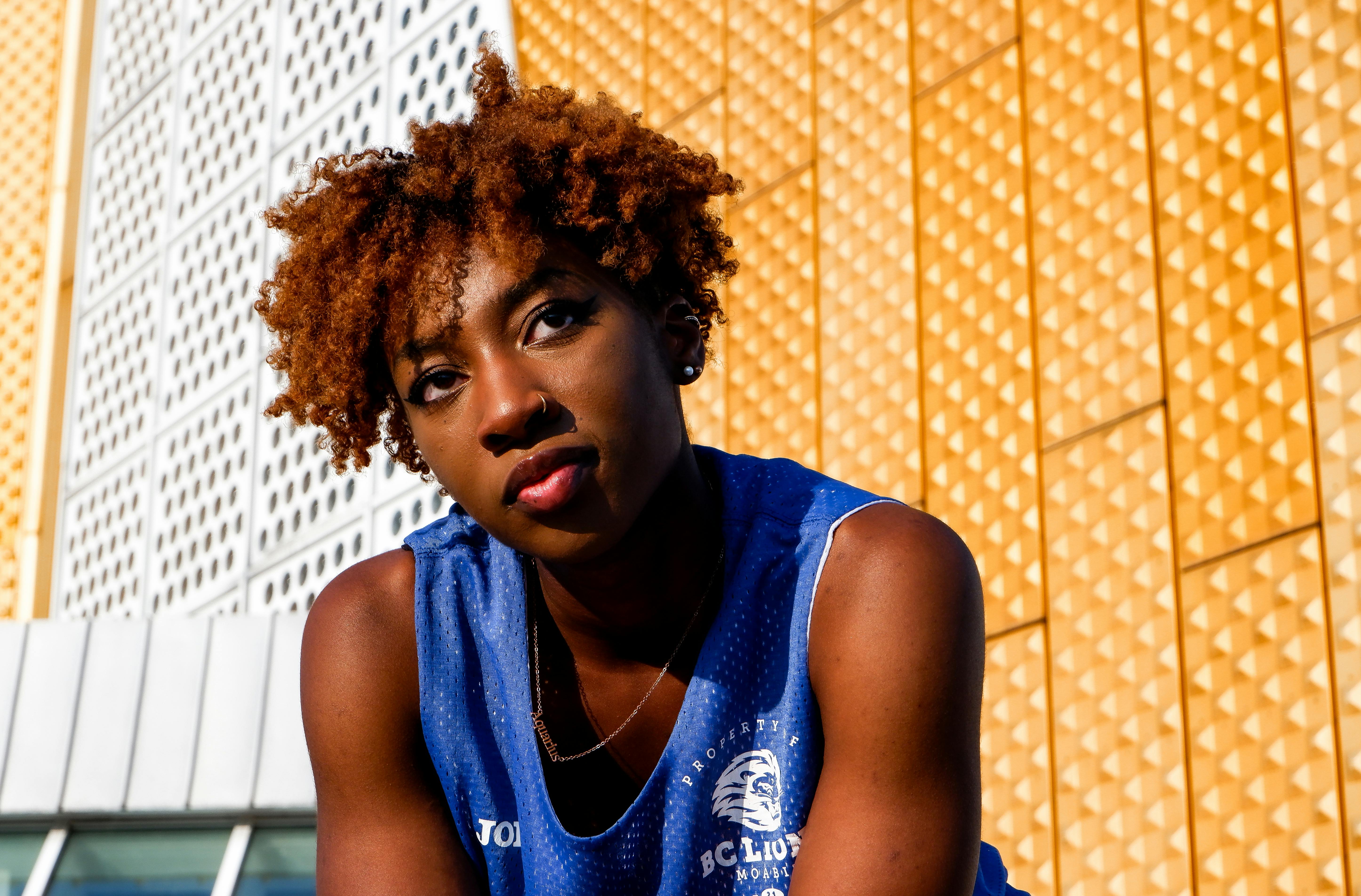 a young woman with curly hair is sitting on a bench