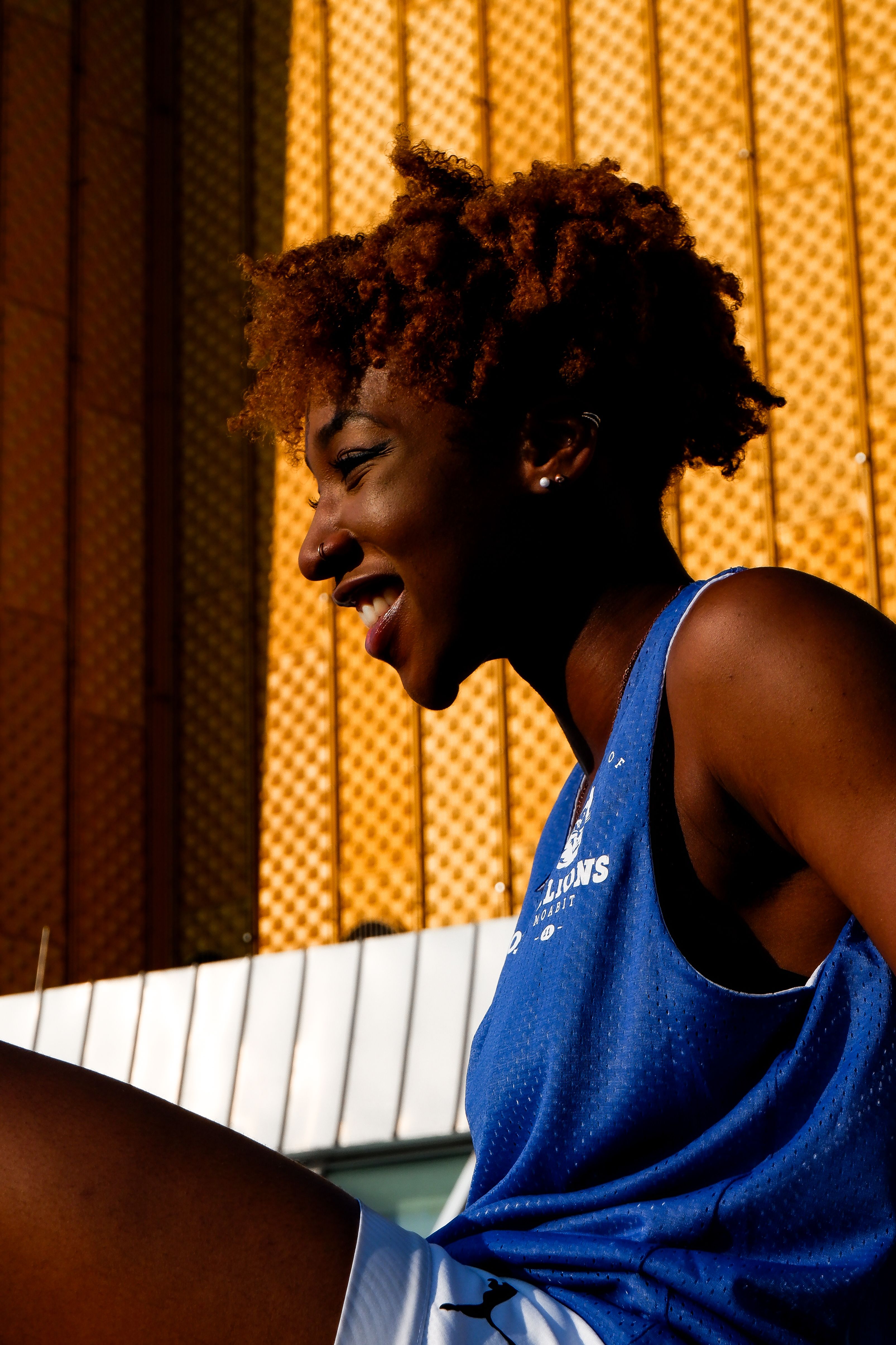 Joyful woman with afro hairstyle in vibrant lighting against textured backdrop.