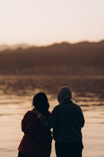 Two friends enjoy a peaceful sunset at Dahab Beach, embracing friendship and tranquility.