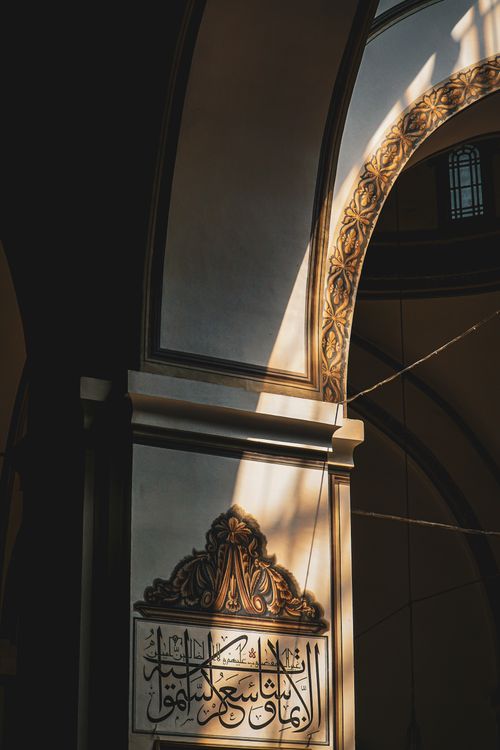 Free Intricately decorated arch inside a mosque in Bursa, Türkiye, with warm sunlight casting shadows. Stock Photo