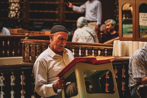 Free Elderly man reading a book inside a traditional Bursa interior setting with ornate decor. Stock Photo