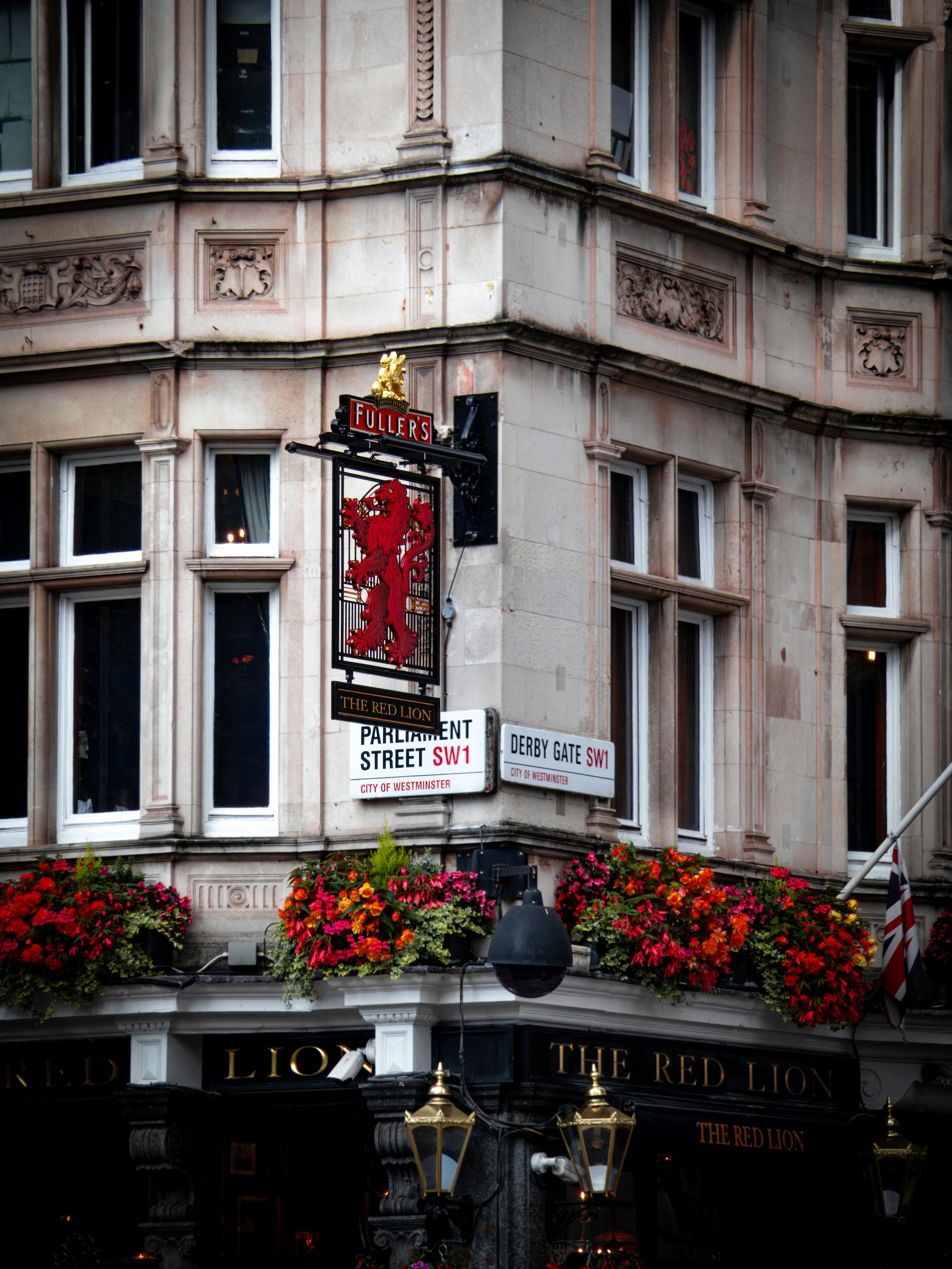 A historic pub facade with vibrant flowers and classic signage in London.