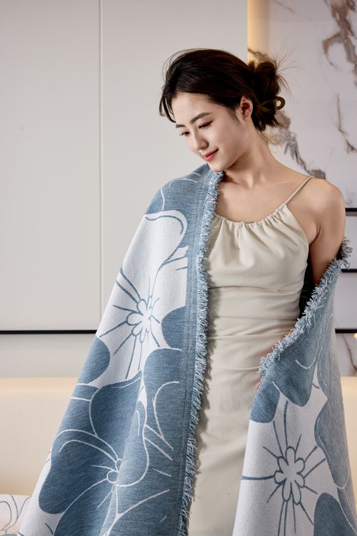 Free A beautiful woman in a cream dress elegantly draped in a floral blanket, showcasing style and luxury. Stock Photo
