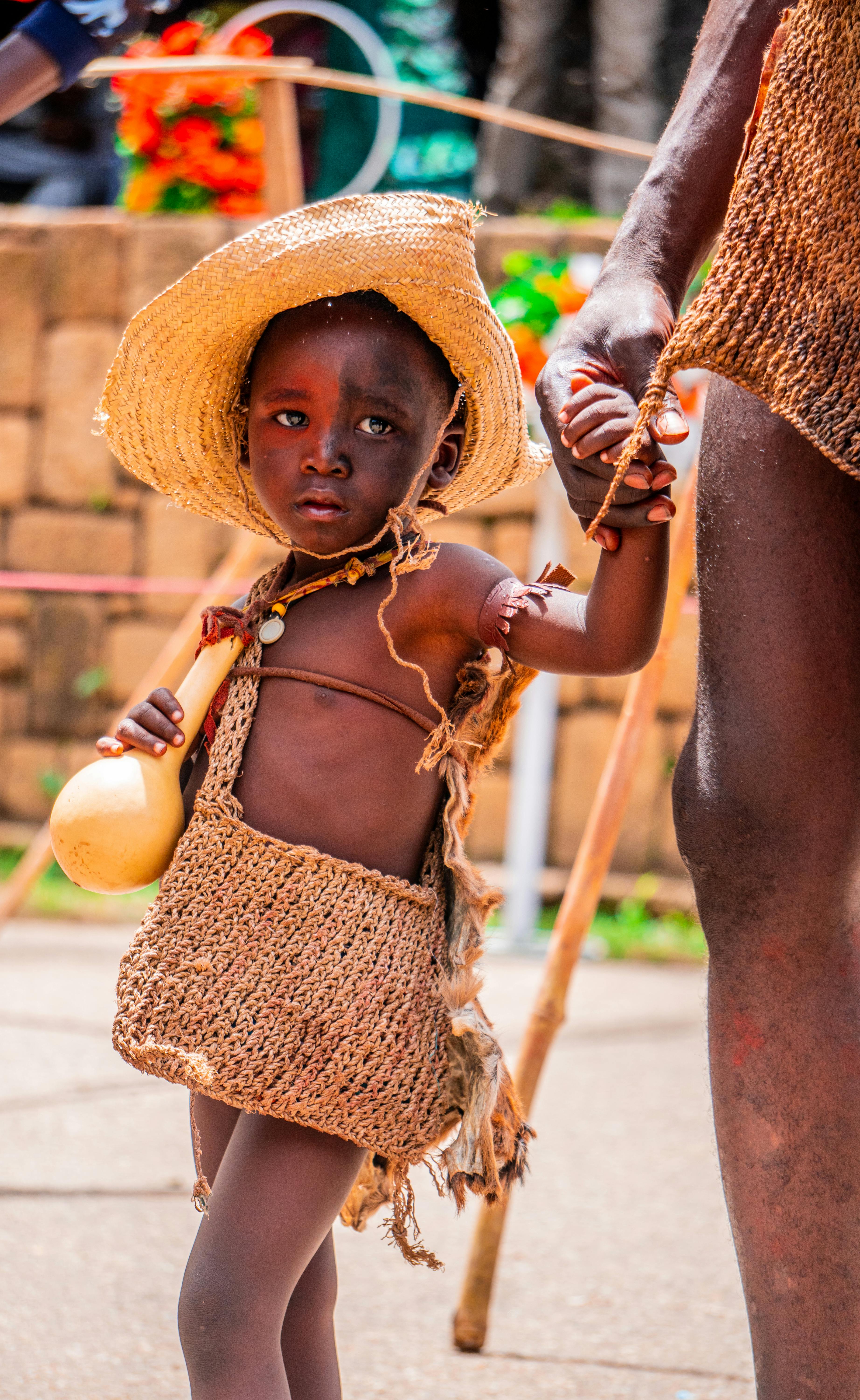 A young african child in a straw hat and dress · Free Stock Photo