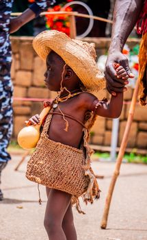 Young child in traditional attire at a cultural festival, outdoors, vibrant setting.