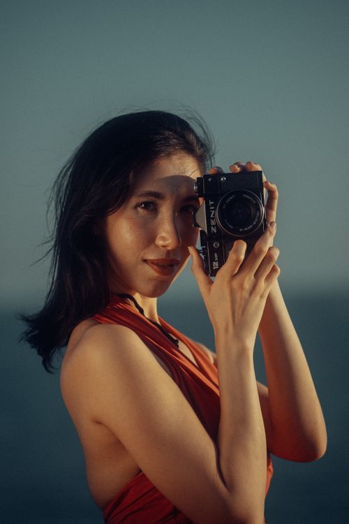 Free Portrait of a woman holding a vintage camera outdoors during the day. Stock Photo