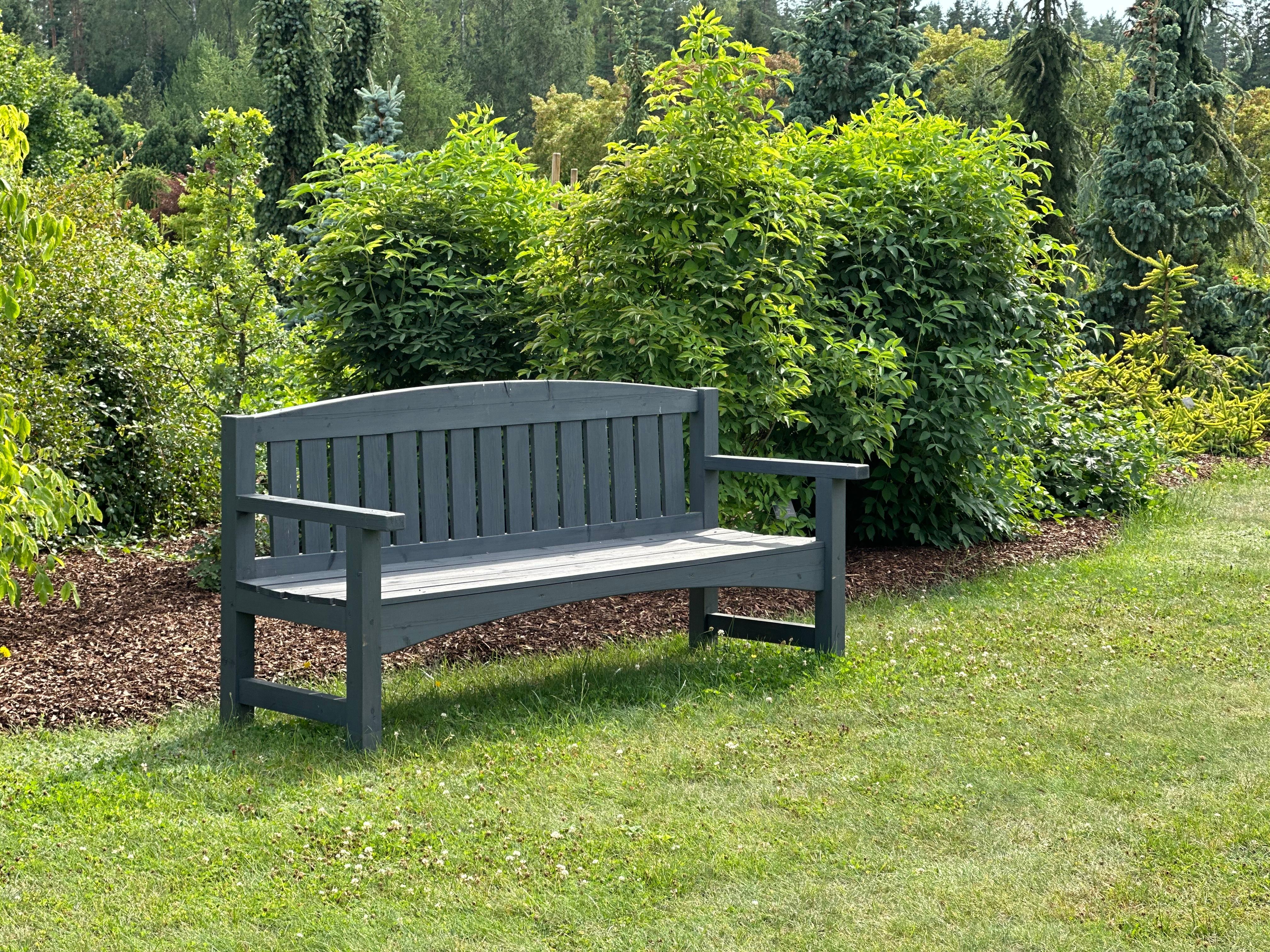 A bench sitting in a garden next to bushes · Free Stock Photo