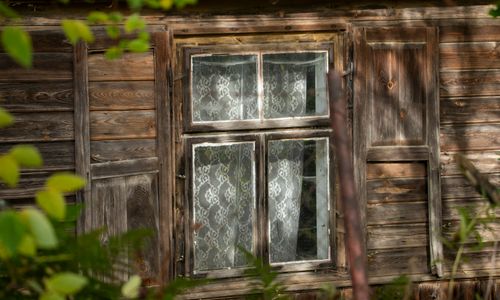 Free Close-up of a wooden window with lace curtains on an old rustic cabin. Stock Photo
