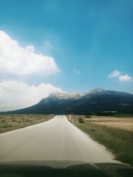 Lonely road leading to a distant mountain under a clear blue sky in summer.