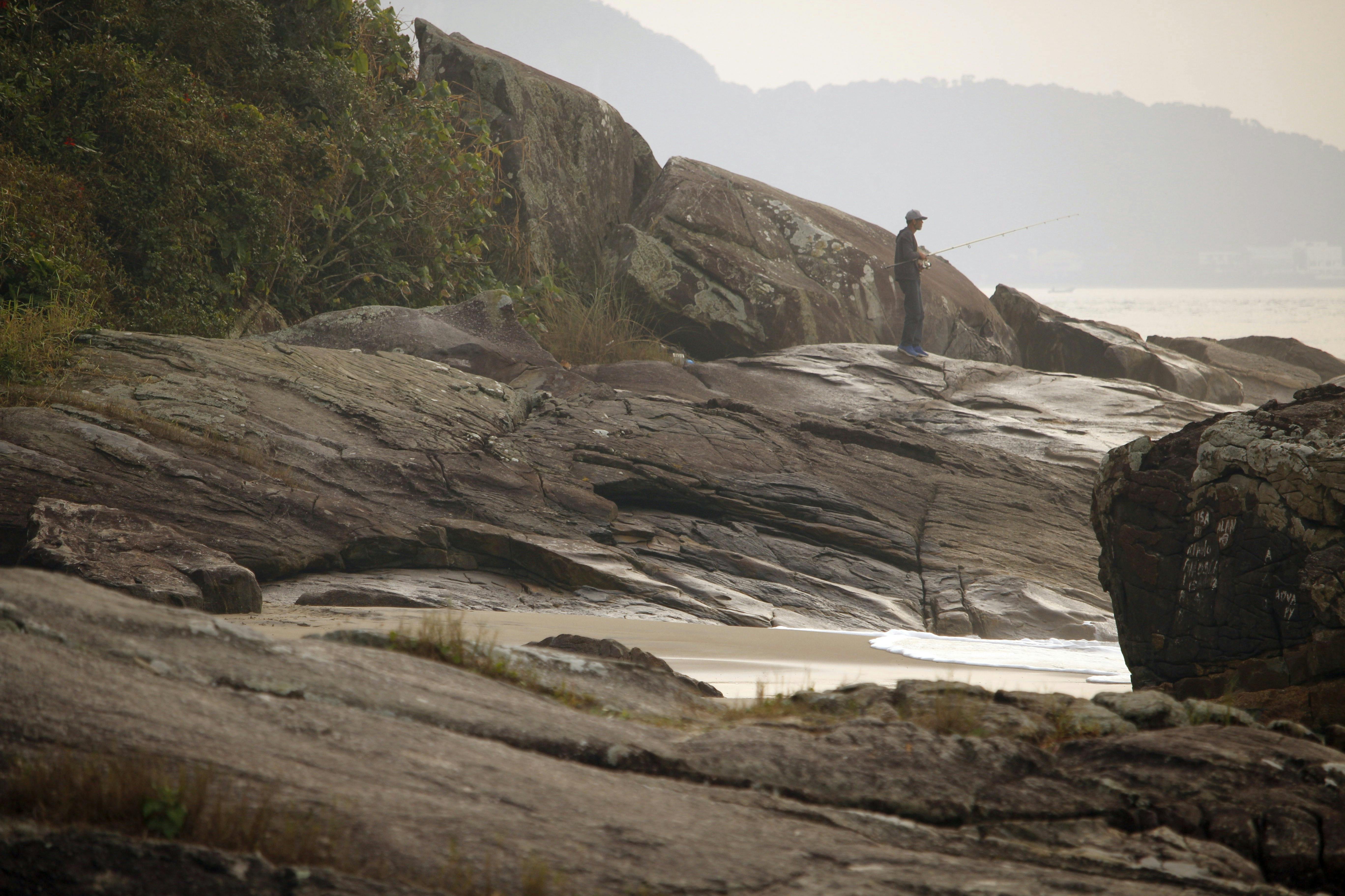 a person is standing on a rock in the ocean