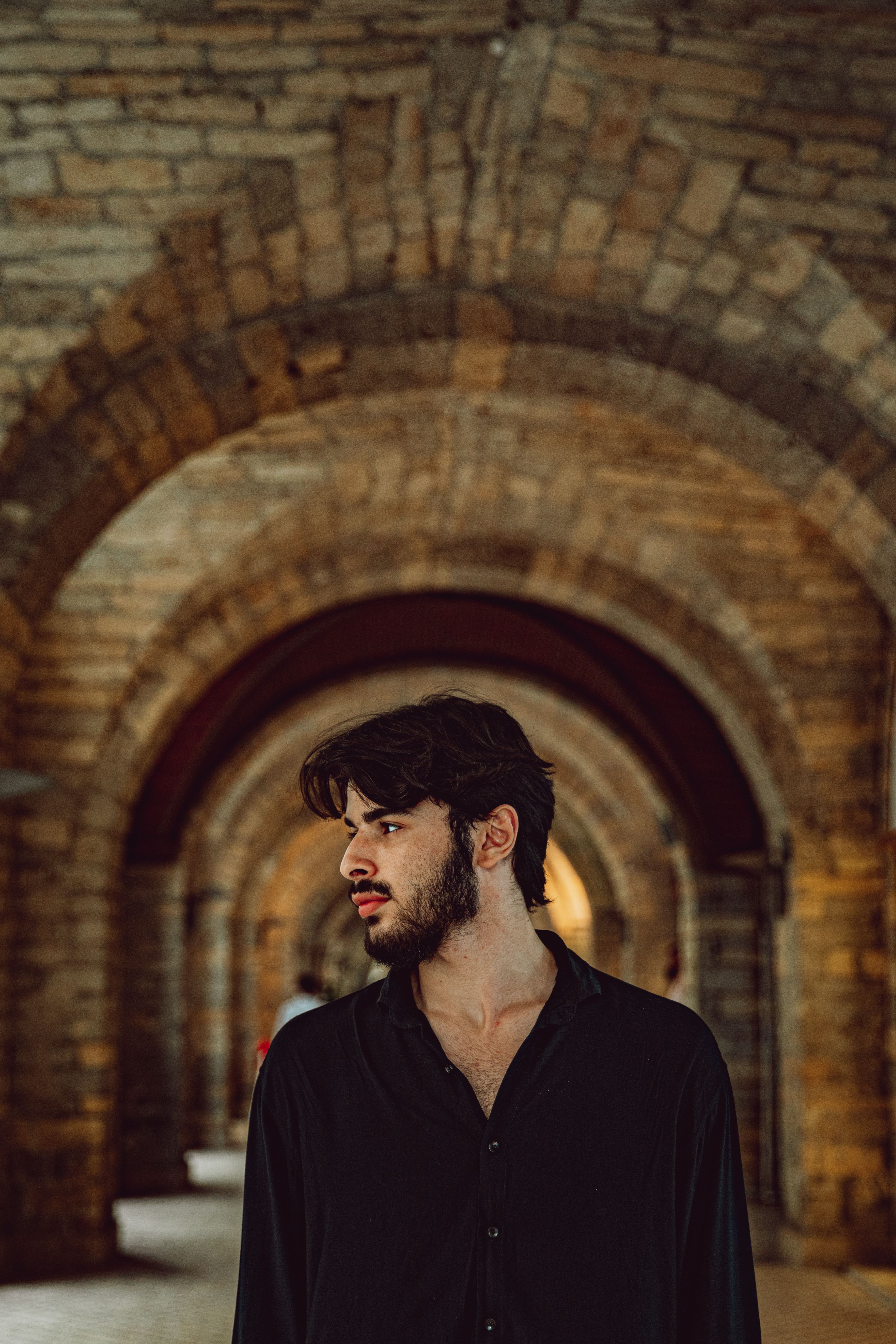 Portrait of a man standing in a historic stone archway in Baku, Azerbaijan.
