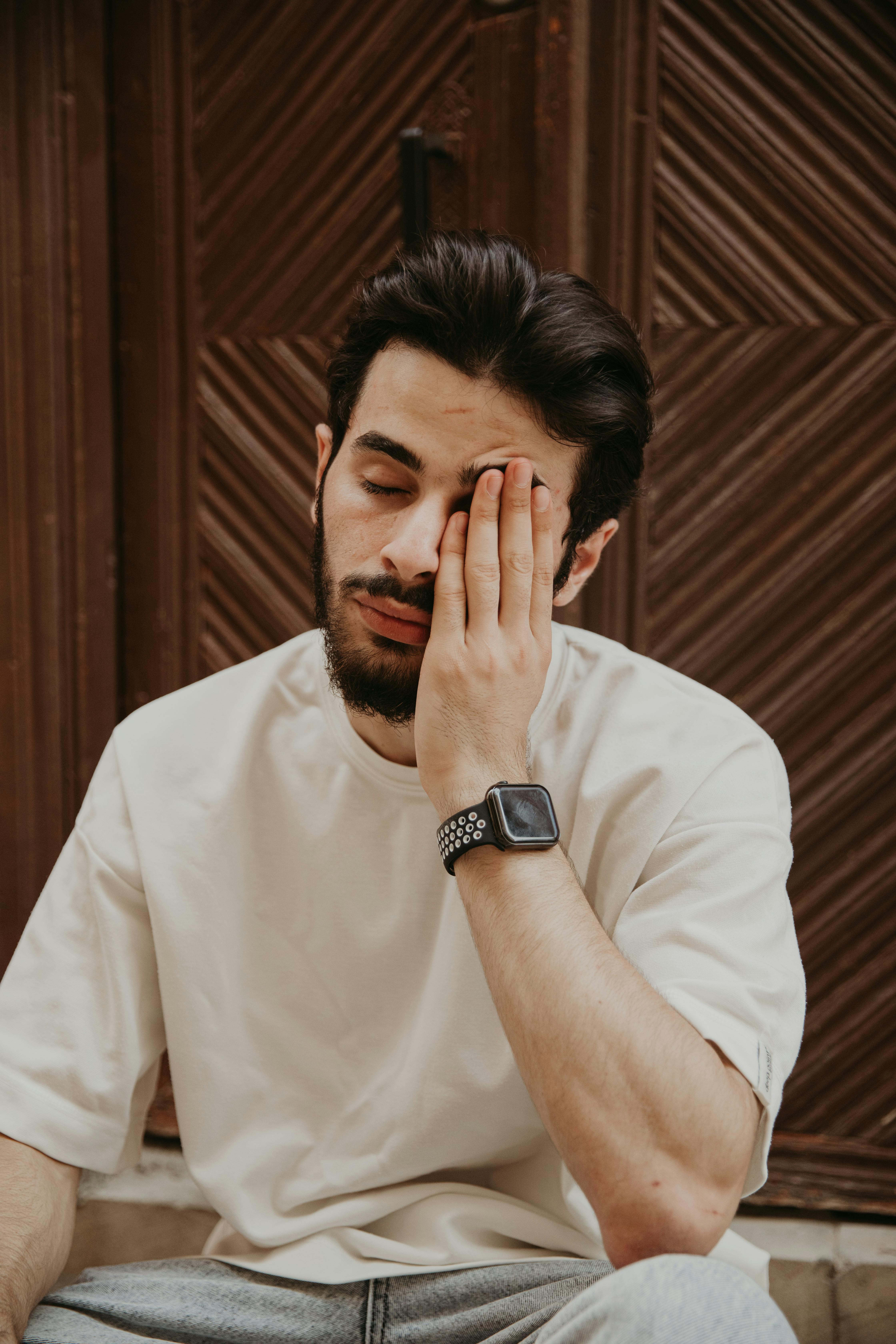 a man sitting on the ground with his hand on his face