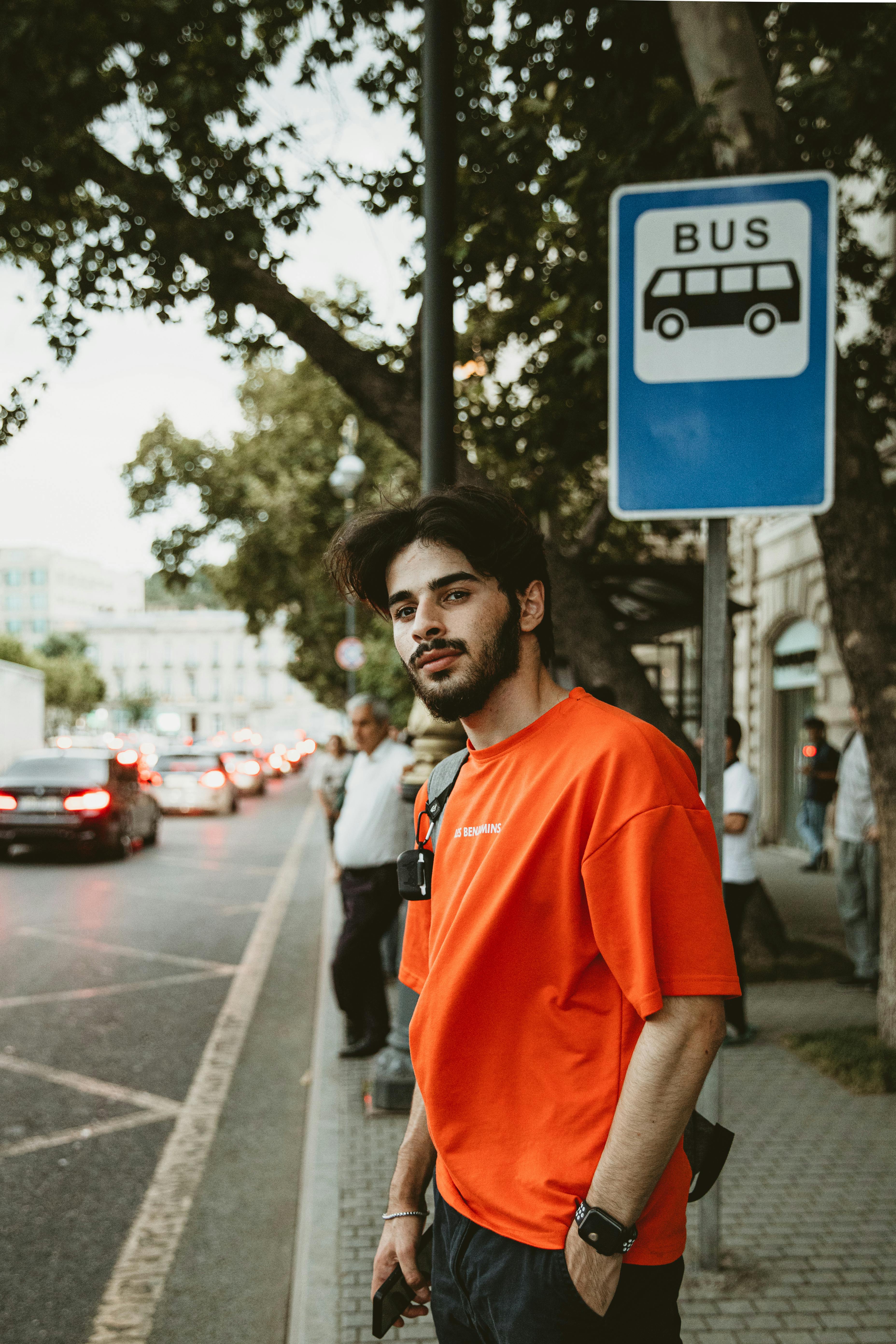 a man in an orange shirt standing on the street