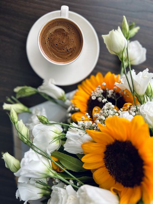 Free Stylish still life of a coffee cup with a vibrant floral bouquet, perfect for decorating or capturing warm moments. Stock Photo