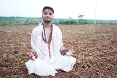 A serene man meditates in a rural field, embodying peace and spirituality.