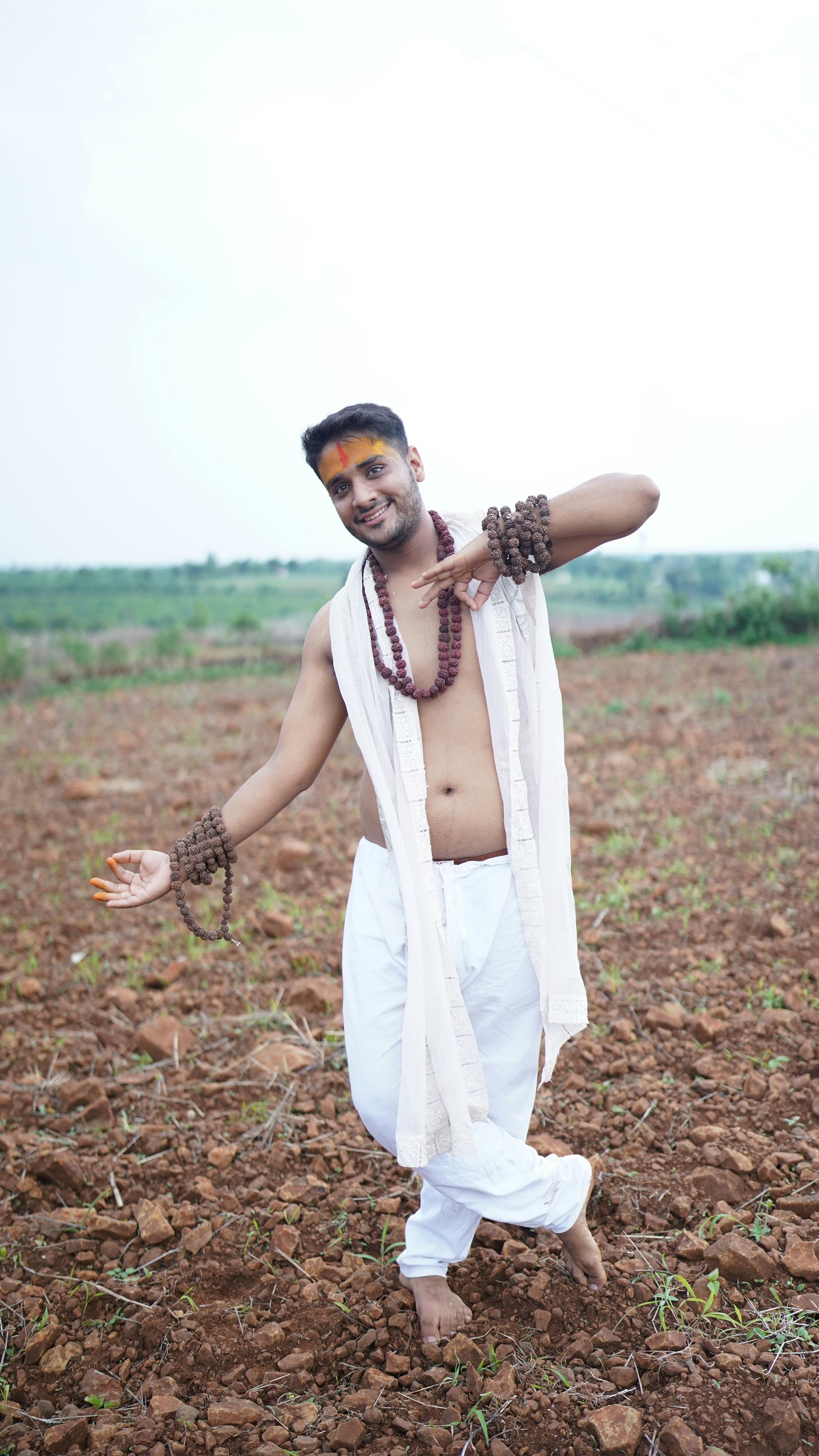 A man in traditional attire dancing in a rural landscape, showcasing cultural richness.