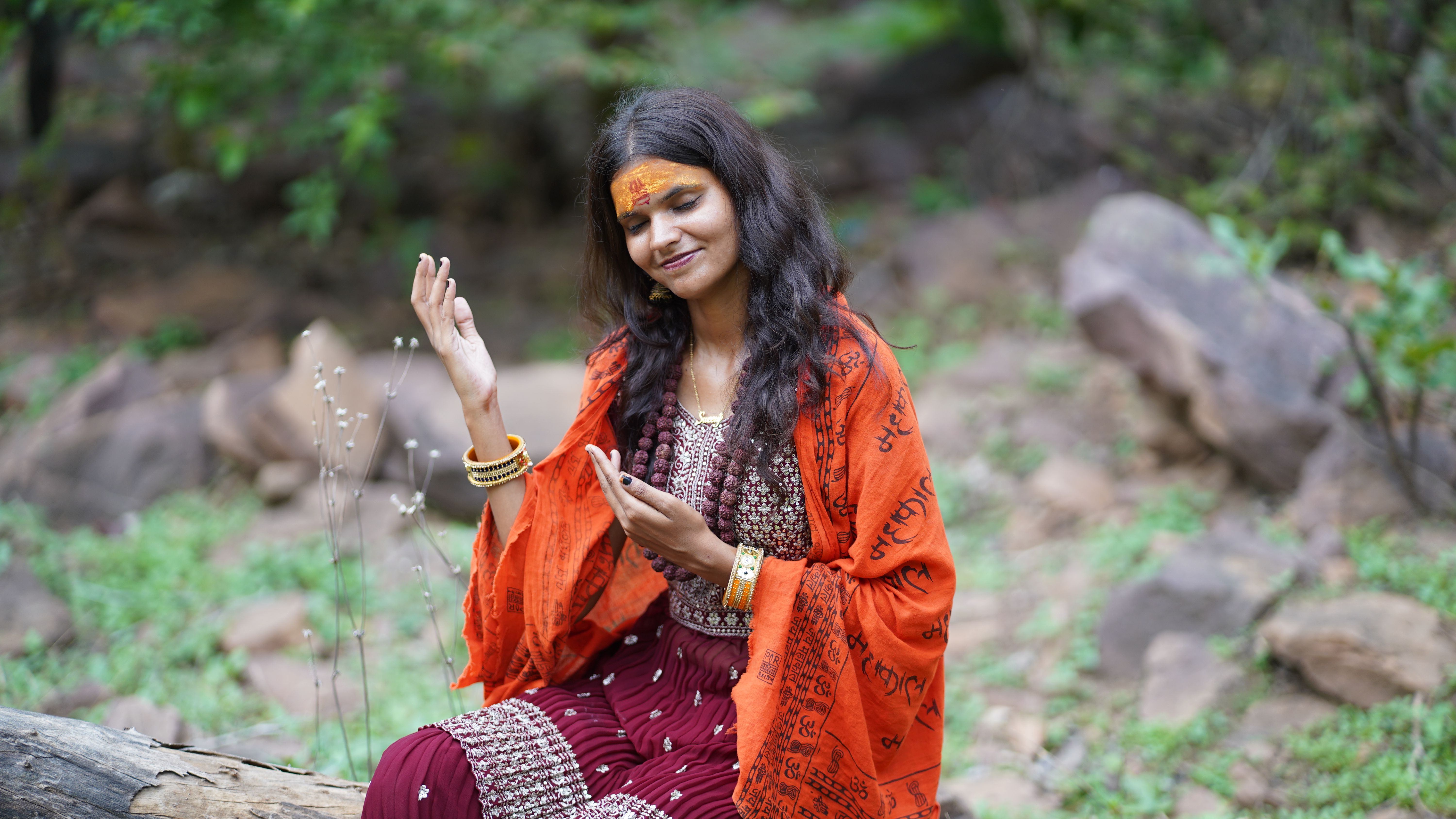 A woman in traditional attire enjoying an outdoor setting with nature.
