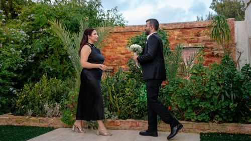 Free A couple shares a moment in a verdant garden, embodying love and elegance. Stock Photo