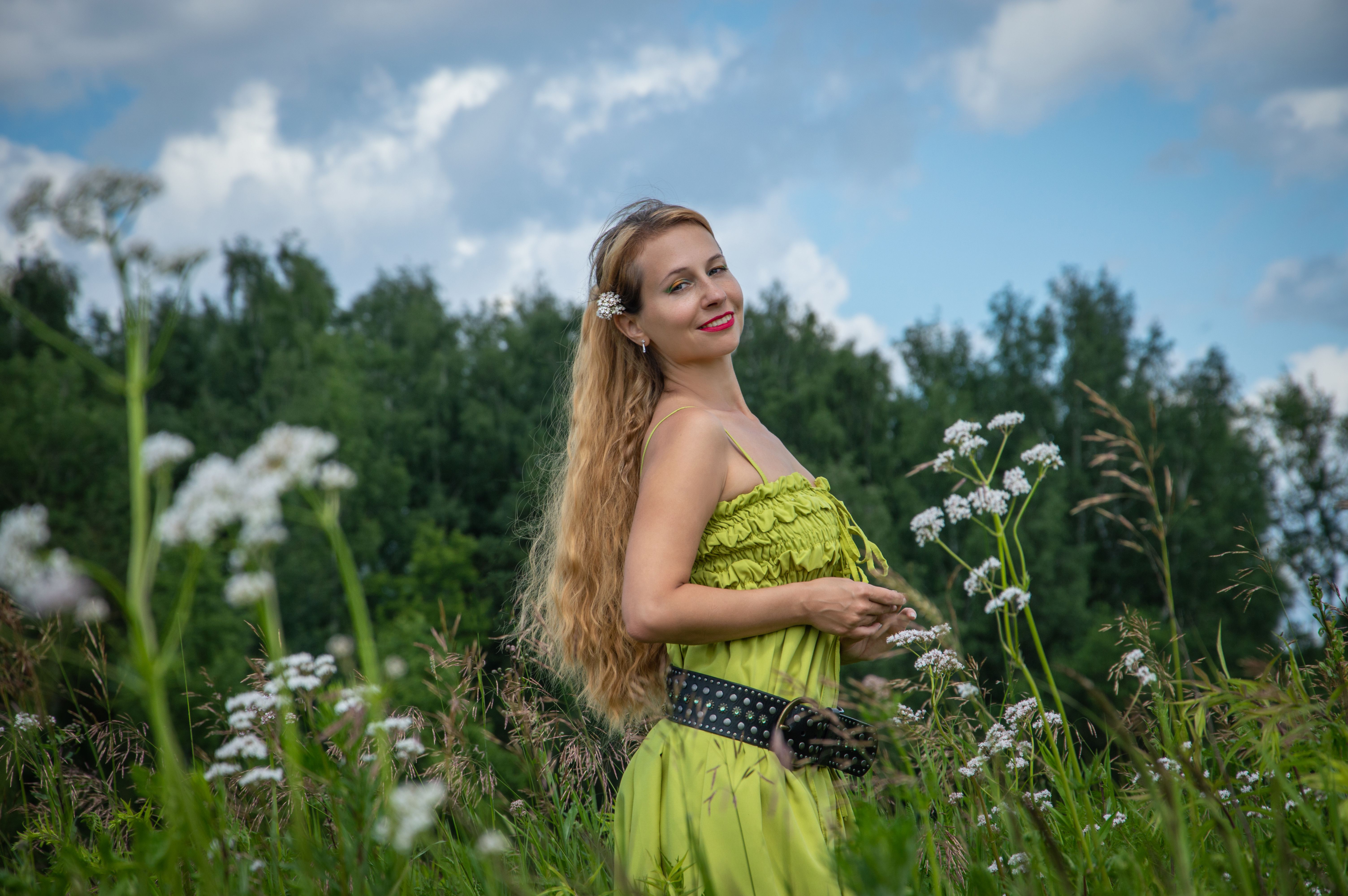 A woman in a green dress standing in a field of flowers · Free Stock Photo