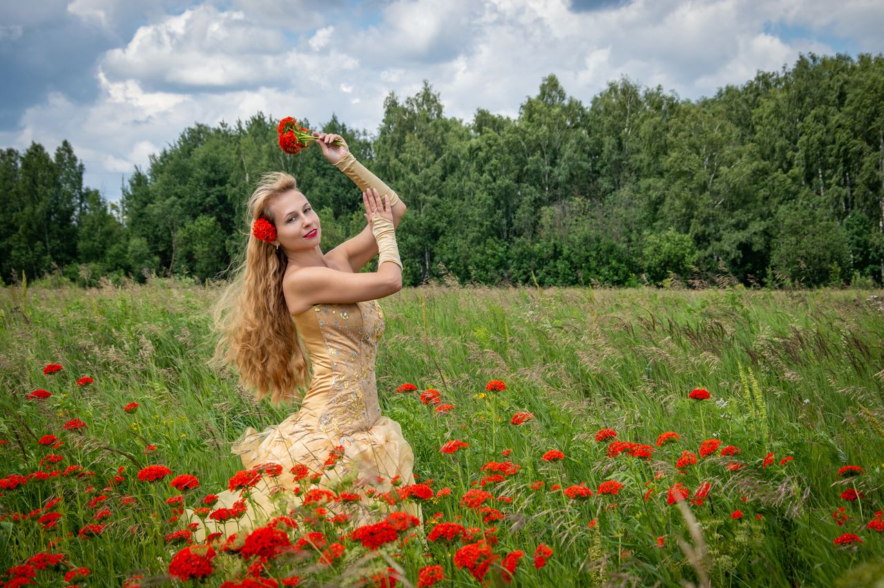 a woman enjoying a bright summer day in a poppy field outdoors