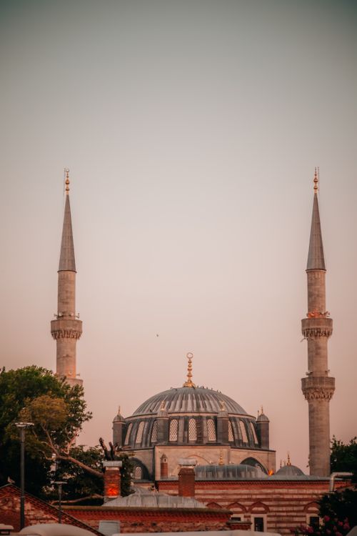 Free Ottoman-style mosque with minarets at sunset, showcasing historical architecture. Stock Photo