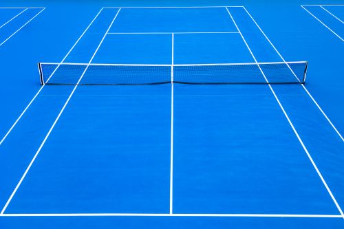Free An overhead view of a vibrant blue tennis court with net and crisp white lines. Ideal for sports themes. Stock Photo