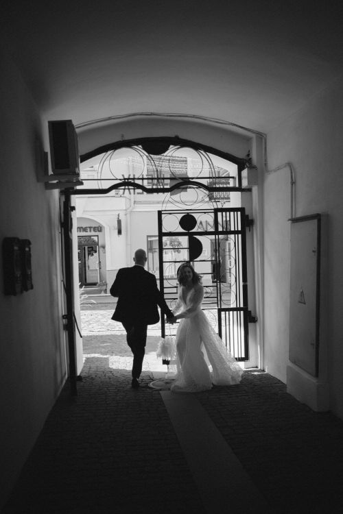 Free A bride and groom seen from behind, exiting a building through an ornate gate. Stock Photo