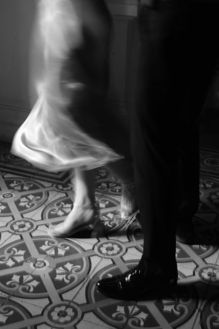 Blurred motion of a couple dancing gracefully on a patterned floor in a classic setting.