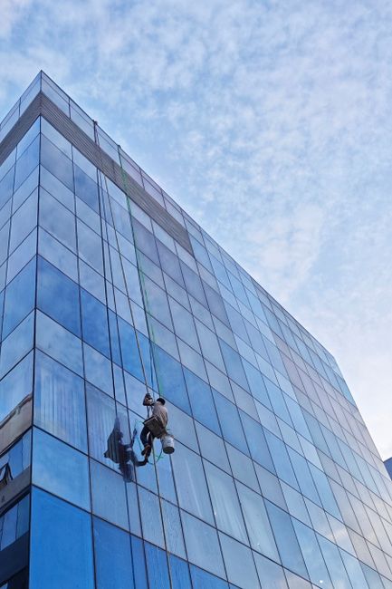 An urban scene showcasing a window cleaner scaling a modern glass building, representing city life.