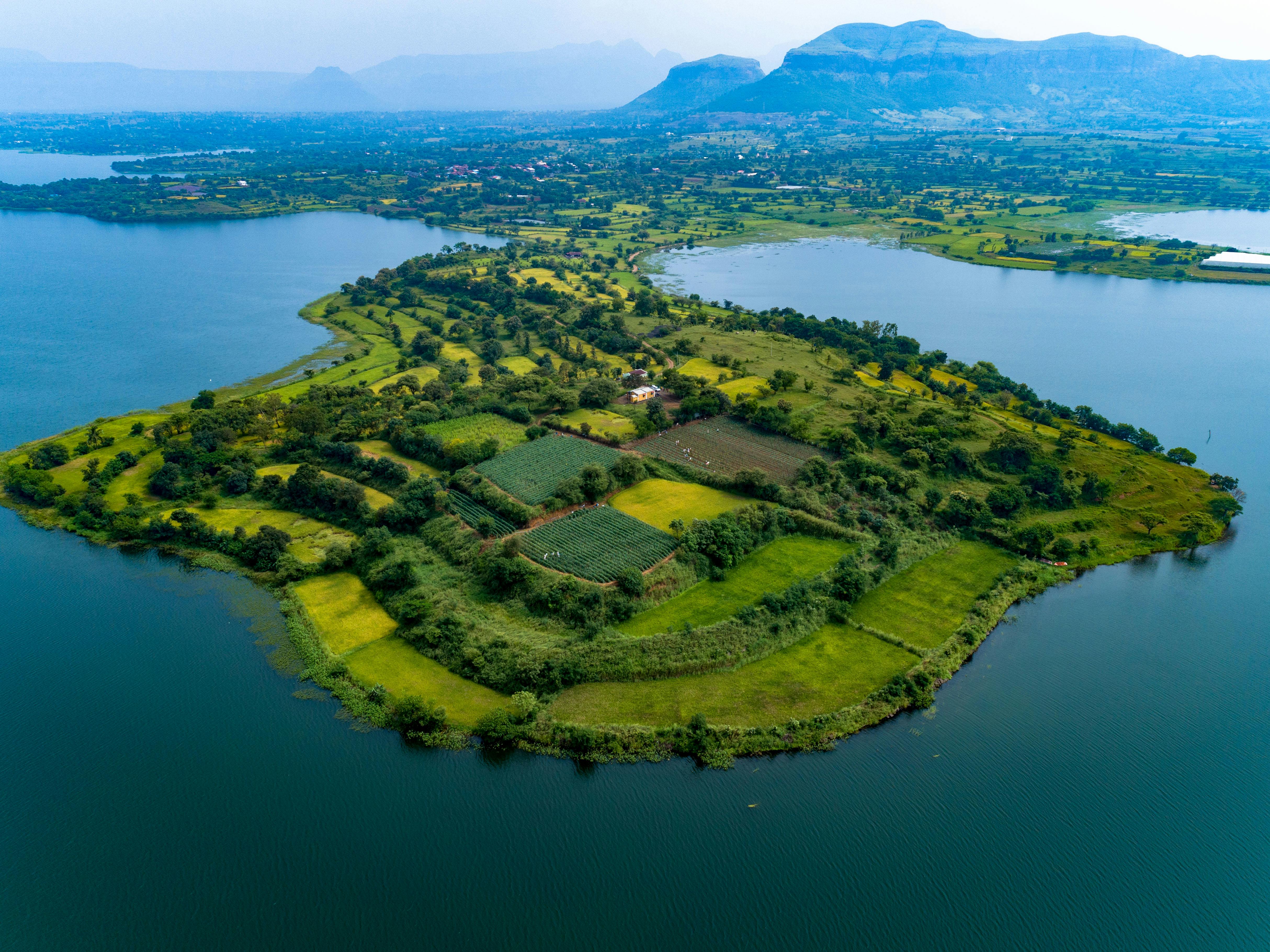 Stunning aerial photo of lush green island in Igatpuri, India surrounded by blue waters.