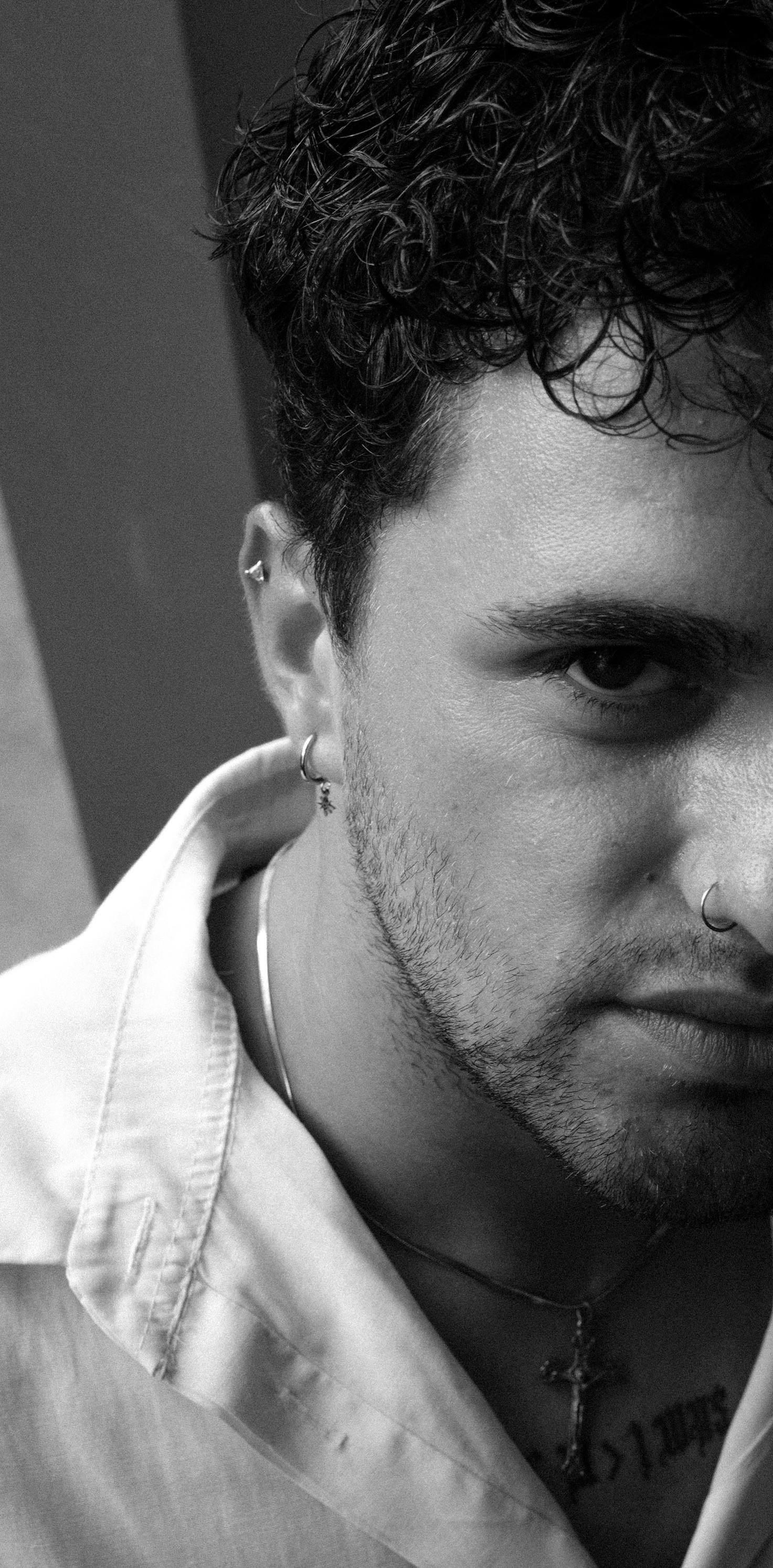 Close-up black and white portrait of a serious young man with piercings.