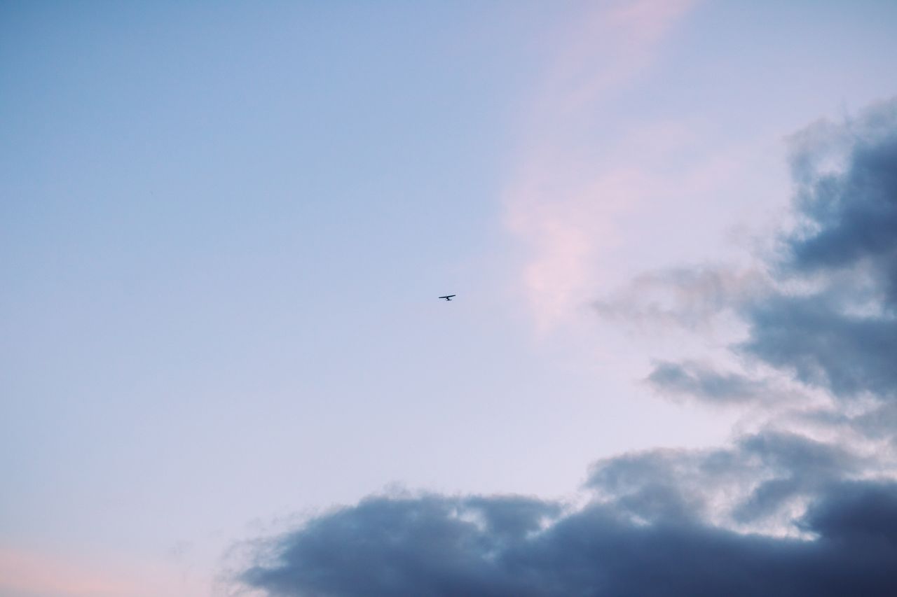 a lone airplane flies high in a vibrant blue sky with soft clouds at s