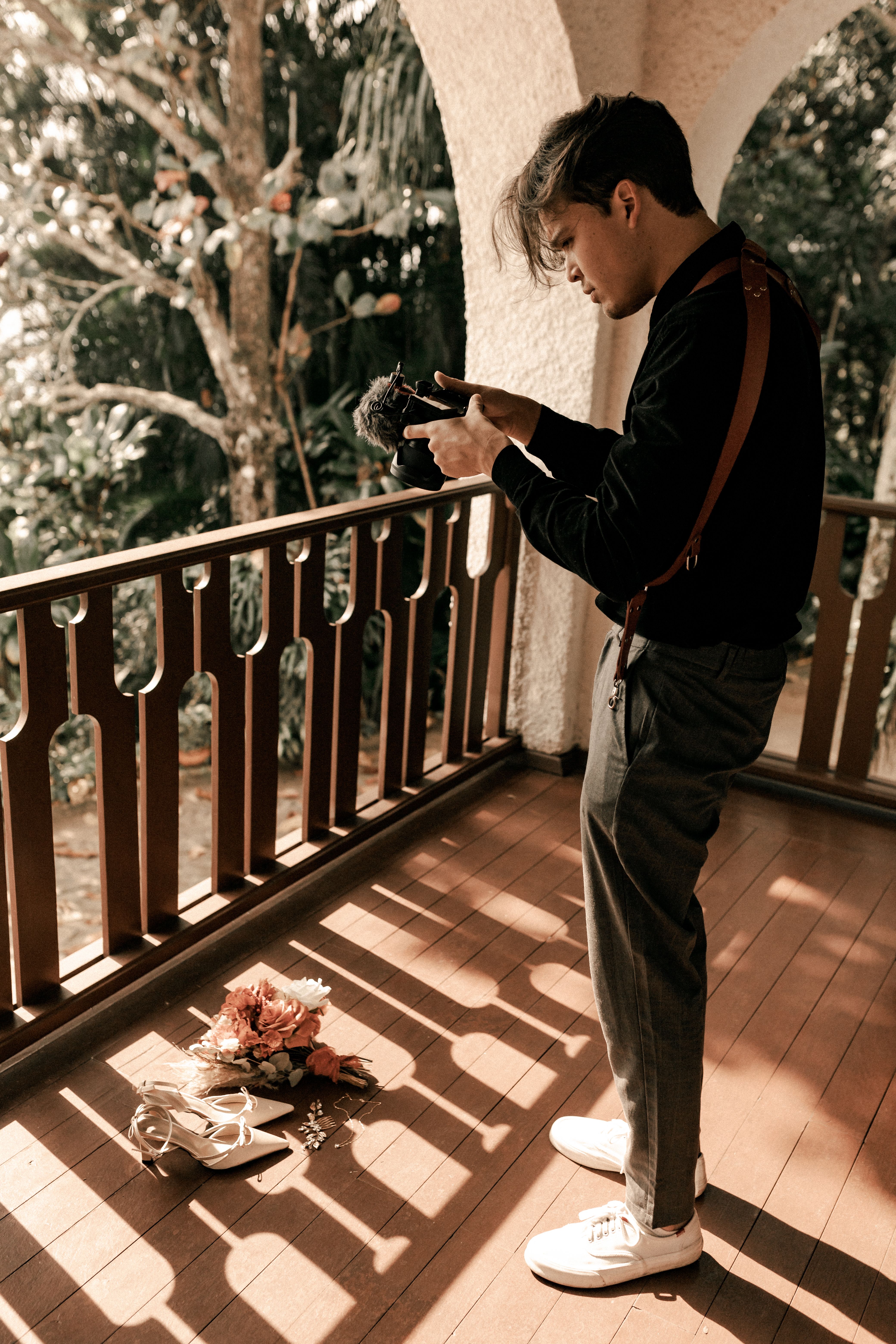 Man on balcony capturing creative shot with camera in natural light.