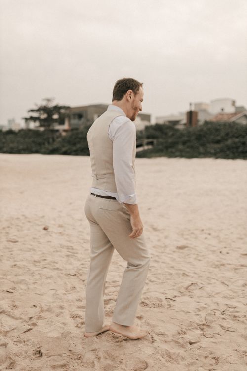 Free A man in a suit leisurely walks barefoot on a sandy beach, offering a blend of business and relaxation. Stock Photo