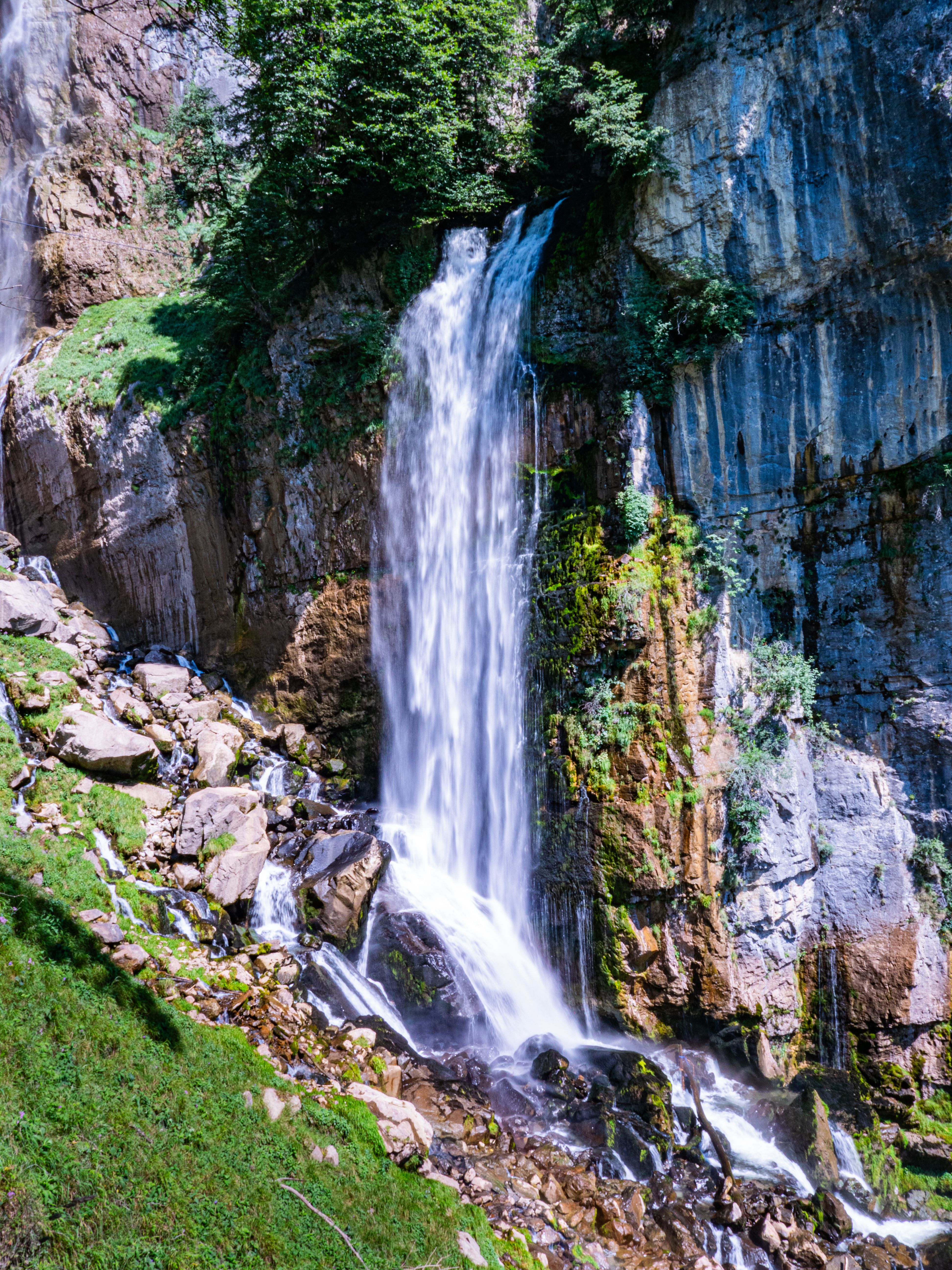 A waterfall is shown in the middle of a green area · Free Stock Photo